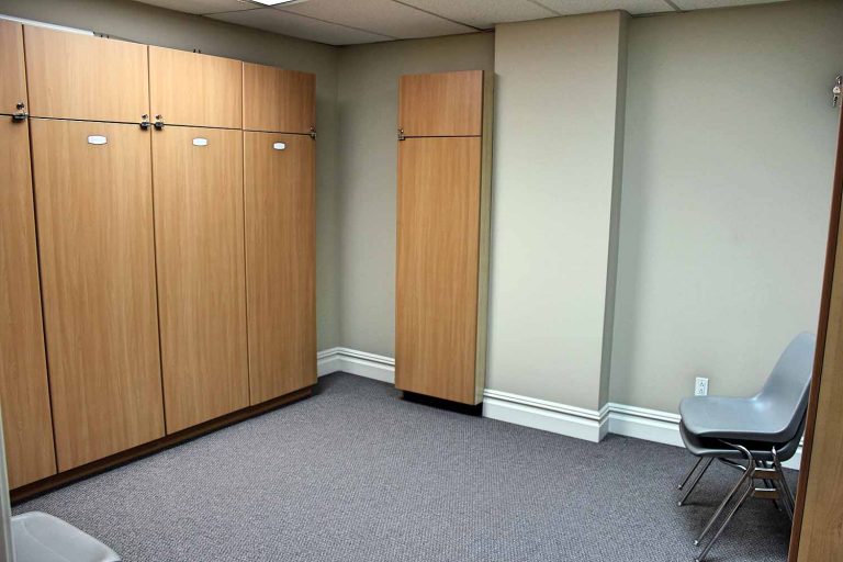 A wall of tall wooden lockers, with a chair beside them