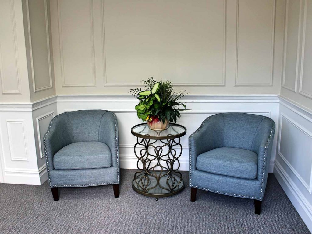 Two blue armchairs beside a small glass table with a plant