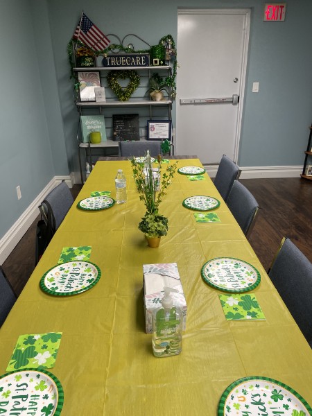 A long table set with St. Patrick’s Day plates and napkins, with a TrueCare sign on a shelf behind it